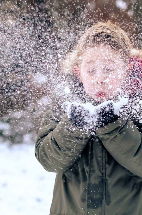 Junge pustet in Schnee