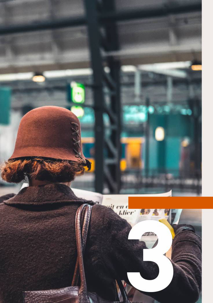 Frau an Bahnsteig mit Zeitung in der Hand